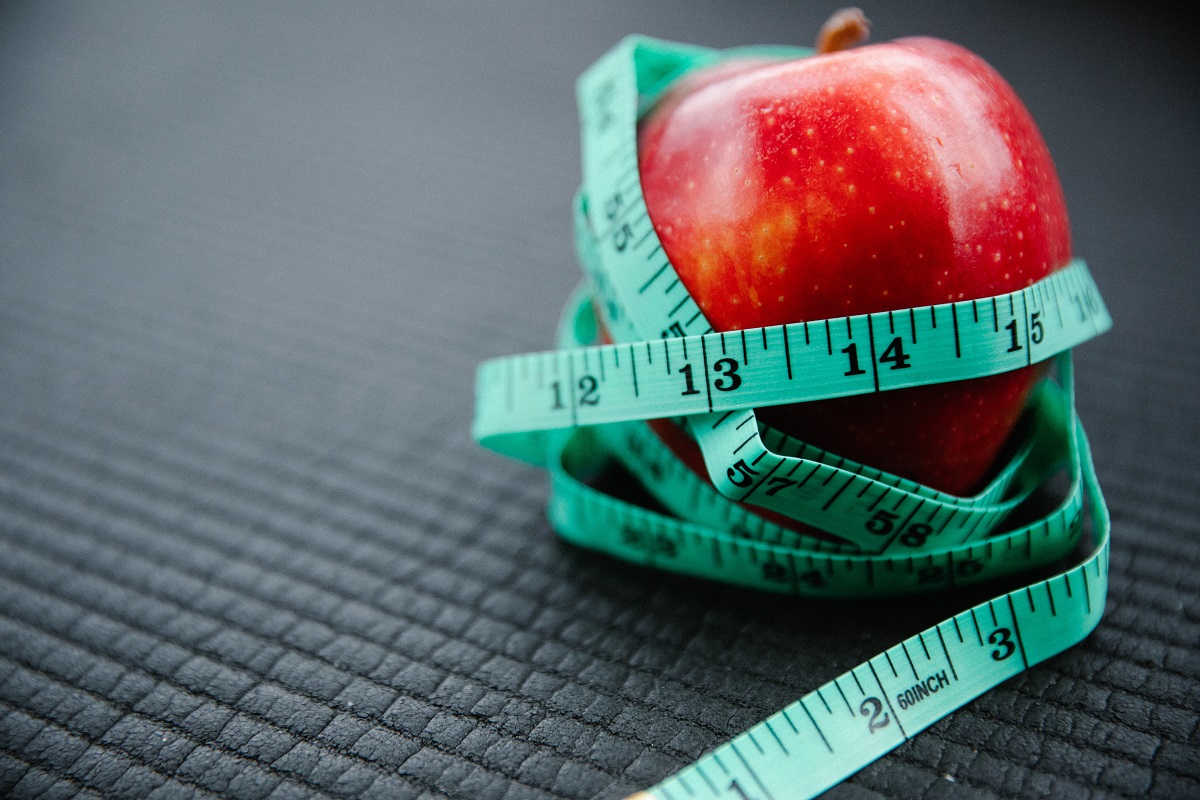 Apple wrapped in tape measure. Learn about the weight inclusive approach to health with Intuitive Nutrition.