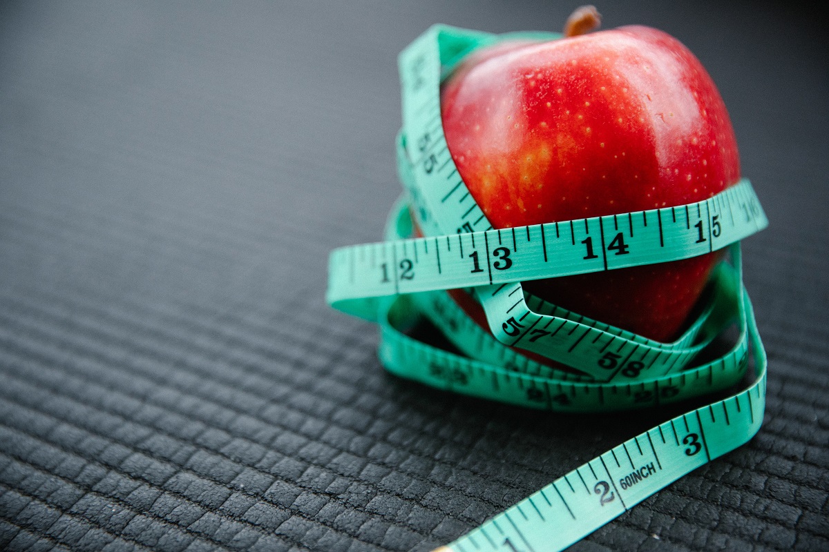 weight-inclusive-approach-intuitive-nutrition Apple wrapped in tape measure. Learn about the weight inclusive approach to health with Intuitive Nutrition.